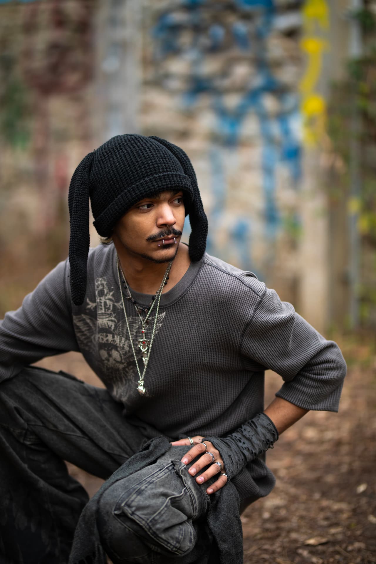Crouched streetwear portrait with layered silver jewelry