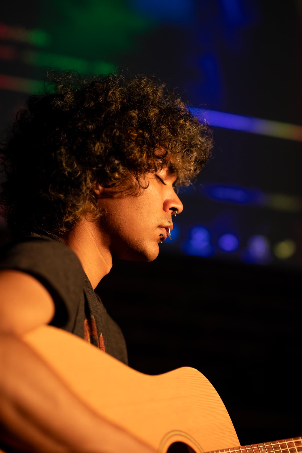 Warm stage-lit profile with acoustic guitar and neon backdrop