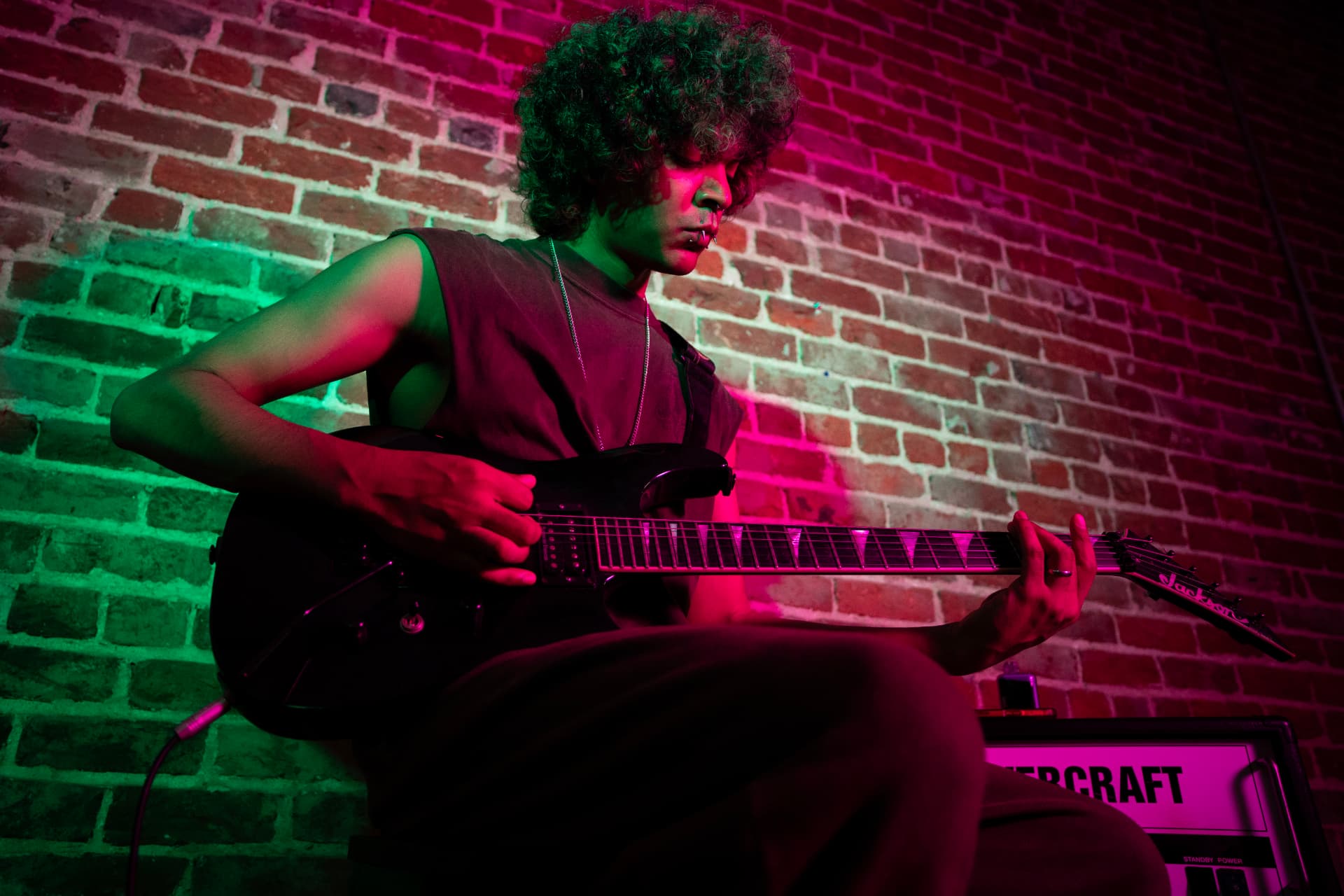Musician playing electric guitar under neon pink and green lights